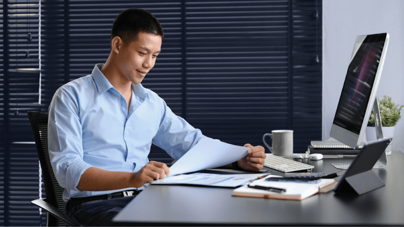 Millennial Businessman Analyzing Graphs And Charts Preparing Economic Report